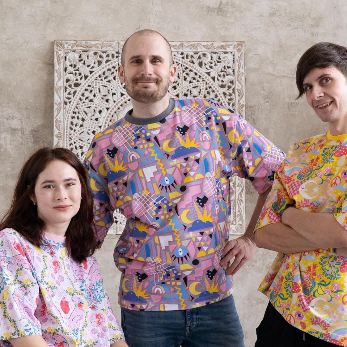 three people standing in boho photo atelier with bright colorful dopamine style unisex oversized t-shirts